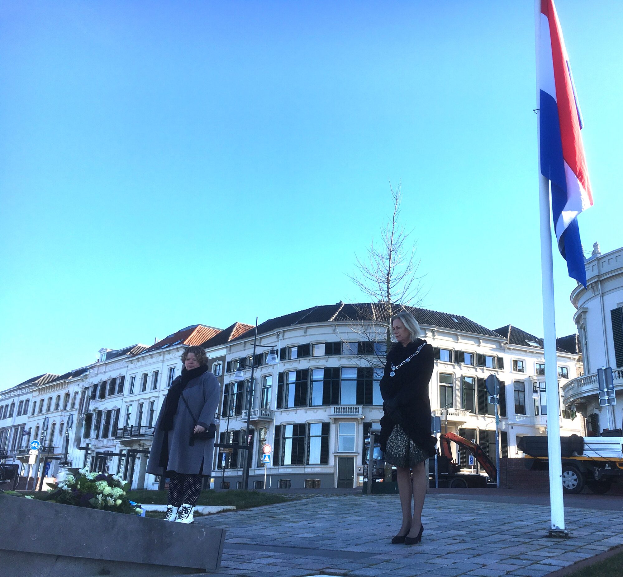 Burgemeester en directeur de Bongerd leggen bloemen bij monument op de IJsselkade