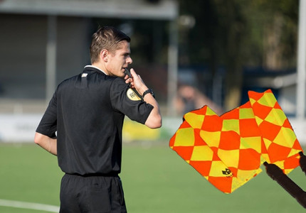 Jonge arbiter hangt de(scheidsrechters)vlag uit